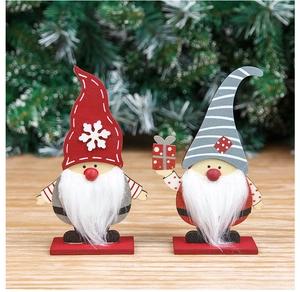 Close-up of handcrafted wooden Christmas gnomes with snowflake hats and gift box props