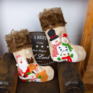 Burlap Christmas stockings with faux fur trim and festive embroidery on leather chair