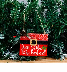Detailed view of red wooden Christmas tag with fun quote and pine cone hanging on a tree