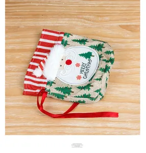 Detail of burlap Christmas gift bag with Santa Claus patch and red drawstring on wood