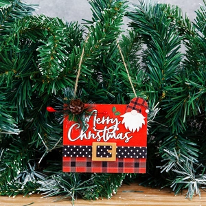 Wooden square Merry Christmas sign with gnome and berries hanging on a green Xmas tree
