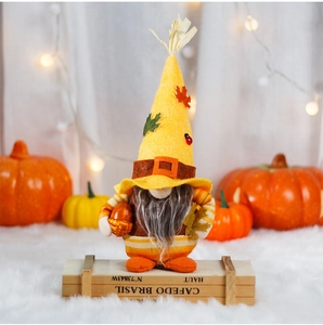 Macro shot of an autumn gnome figurine holding an acorn with a decorative pumpkin background