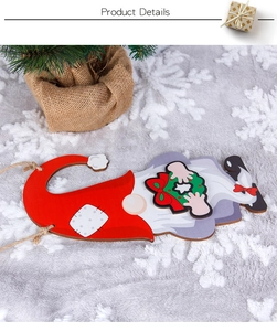 Close-up of wooden Christmas gnome ornament with green wreath and festive holiday decor