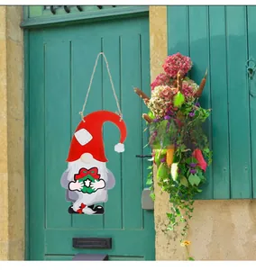 Detail of a DIY wooden gnome door hanger with a red hat and green Christmas wreath