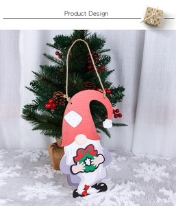Close-up of wooden Christmas gnome ornament with red hat and wreath on a festive tree