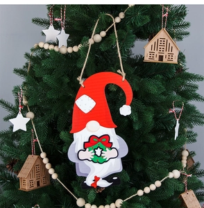 Close-up of a festive gnome door sign with a green wreath on a Christmas tree branch