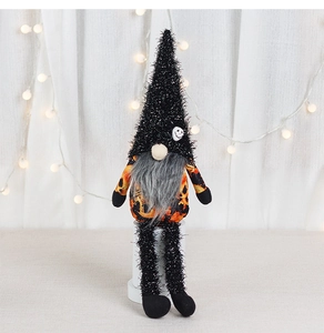 Detail of Halloween gnome plush toy with long legs and pumpkin pattern on white background