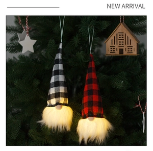 Detail of two LED Christmas gnomes with plaid hats glowing on a green Christmas tree