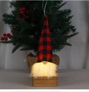 Detail of a glowing Christmas gnome with red and black buffalo plaid hat on wooden base