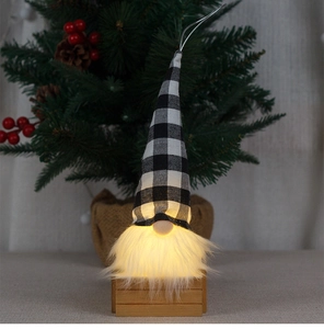 Detail view of a glowing Christmas gnome with black and white plaid hat and LED warm light