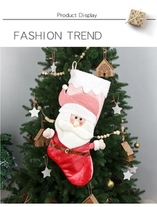 Detail of 3D Santa plush Christmas stocking in pink and red hanging on a festive tree