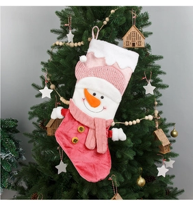 Pink snowman Christmas stocking hanging on tree with plush cuff and knit scarf details