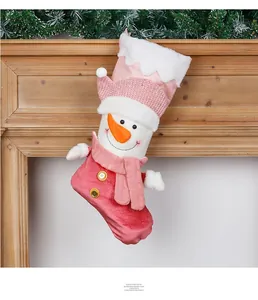 Detailed view of a pink plush snowman Christmas stocking hanging on a wooden fireplace