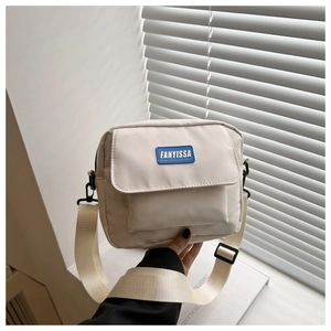 Detail of minimalist nylon crossbody bag featuring a front pocket and adjustable strap