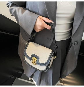 Détail du sac selle rétro en toile beige et cuir noir avec des coutures blanches fines