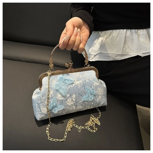 Détail d'un sac jacquard bleu avec broderie papillon 3D et poignée en métal ciselé