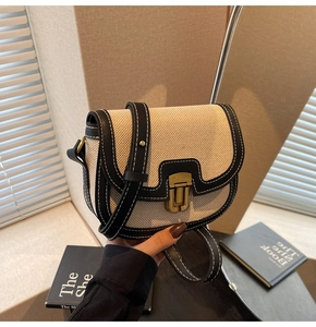 Detail showing beige canvas and black leather saddle bag with bronze snap closure