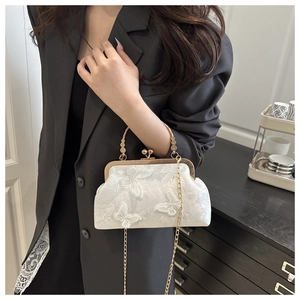 Vue détaillée d'un sac à main en dentelle blanche avec appliques papillons et chaîne d'or