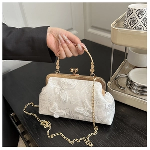Détail du sac en dentelle blanche avec papillons 3D et poignée dorée aux motifs gravés
