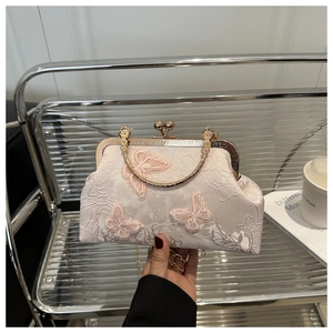 Détail d'un sac bandoulière en satin vintage avec broderie papillon 3D rose et chaîne