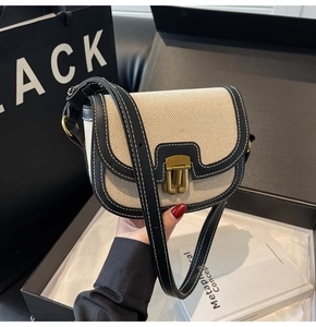 Detail shot of vintage saddle bag featuring beige canvas with black leather trim and metal lock
