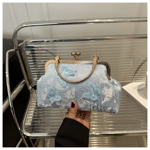 Détail du sac papillon brodé bleu clair avec bandoulière chaîne dorée et poignée en métal
