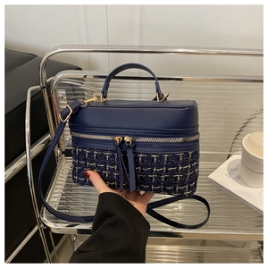 Detail of navy blue box bag showing tweed patchwork and leather tassel decoration