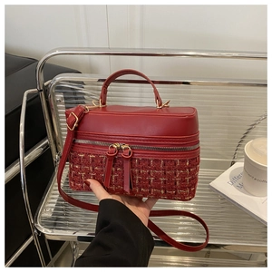 Detail of red tweed handbag with gold metallic threads and leather texture on a cart