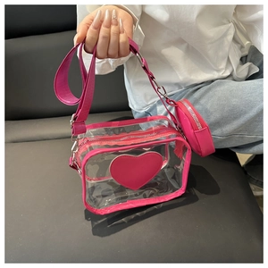Detalle de bolso bandolera de PVC transparente con corazón rosa y monedero redondo a juego
