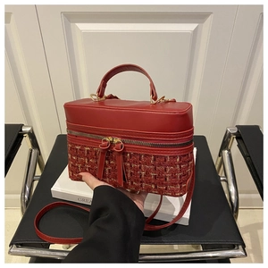 Detail view of red tweed box handbag featuring golden zippers and a detachable shoulder strap