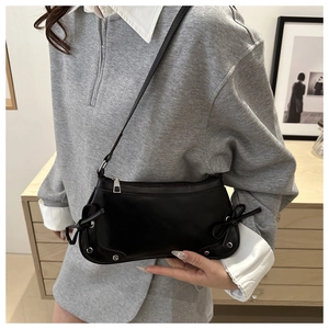 Detail of black PU leather shoulder bag featuring silver rivets and stylish bow accents