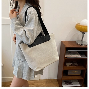 Close-up of cream canvas tote bag with black leather straps showing large capacity