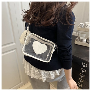 Dettaglio della borsa a tracolla in PVC trasparente con cuore bianco e mini pochette