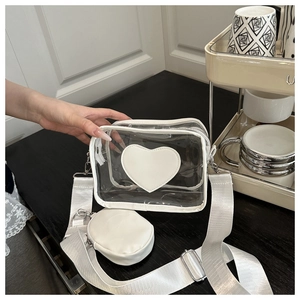 Primer plano de bolso bandolera de PVC en forma de corazón con ribetes de cuero blanco