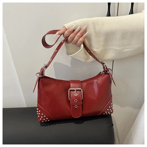 Detail of red faux leather baguette bag with silver buckles and punk style metal studs