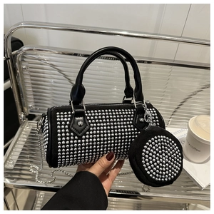 Macro detail of black cylindrical rhinestone handbag with silver chain strap and coin purse