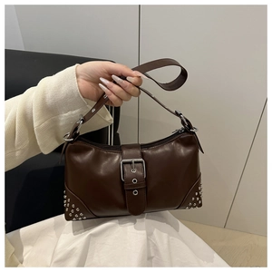Detail view of dark brown leather underarm bag featuring silver rivets and metal buckle