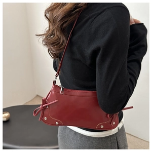 Detail view of burgundy retro underarm bag with silver studs and bow design on shoulder