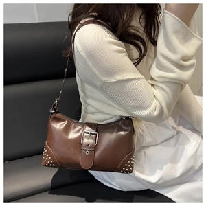 Close-up of brown vintage leather baguette bag with silver rivets and large buckle detail