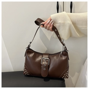 Detail of dark brown leather shoulder bag featuring silver rivets and metal buckle