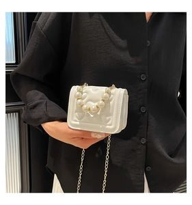 Detail of white quilted mini bag featuring large pearl handle and gold chain strap