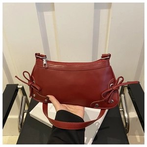 Detail of red faux leather shoulder bag with side bow drawstring and silver hardware