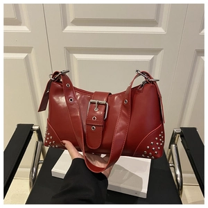 Detail of red leather shoulder bag with silver rivets and metallic buckle accents