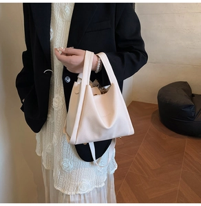 Detailed macro view of cream litchi texture leather handbag with folded triangle design