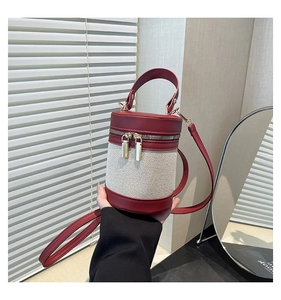Detail of red leather and cream canvas cylinder bag with golden dual zippers