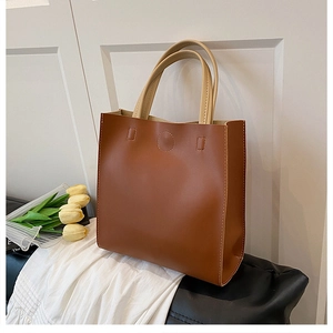 Macro view of brown minimalist tote bag featuring contrast handles and fine stitching details
