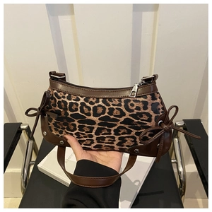 Detail of leopard print baguette bag with brown leather trim and side bow accents
