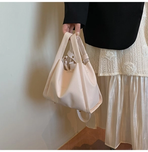 Detail of lychee textured leather cream bucket bag with fashion print and handle