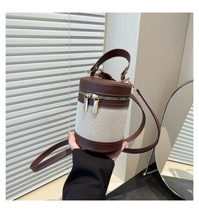 Detailed close-up of a cylinder bucket bag with contrast brown faux leather and canvas panels