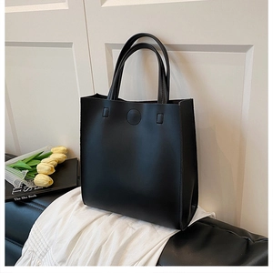 Detail of black leather tote bag featuring round embossed texture and double flat handles
